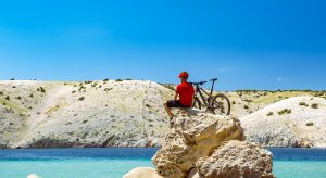 mountain biker on top of rock staring at lake
